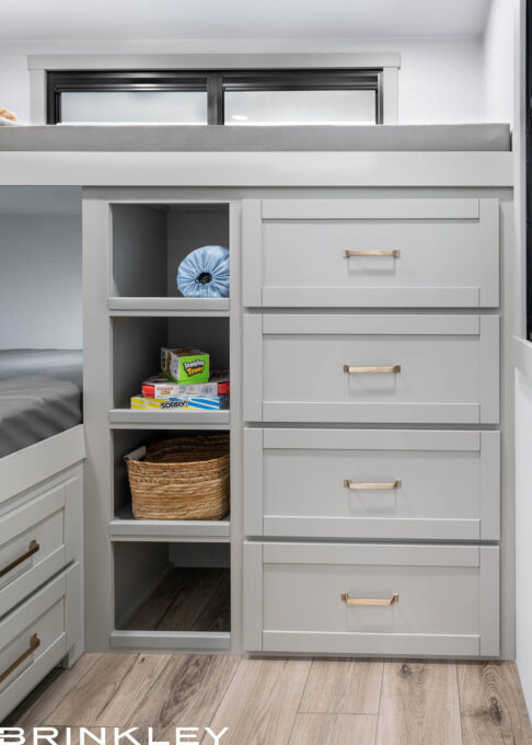 Integrated bunk bed ladder and dresser in a Brinkley Model Z 2810 Fifth Wheel, featuring four storage cubbies built into the steps and a white four-drawer dresser for maximum organization.