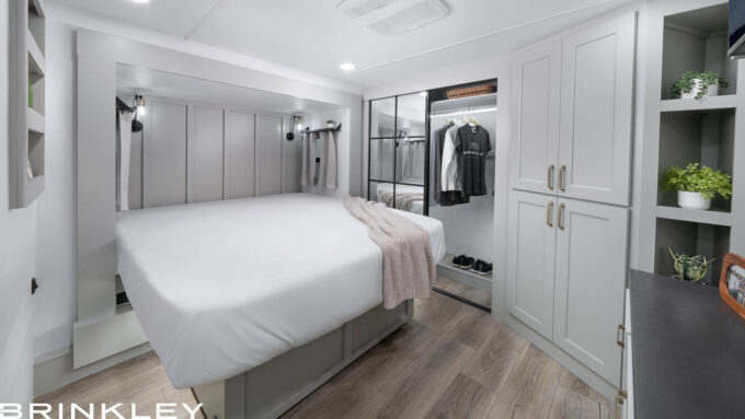 Interior of a Brinkley RV Model Gx 3500x bedroom featuring a king-size bed with a premium Bamboo memory foam mattress, surrounded by windows and large closet. 