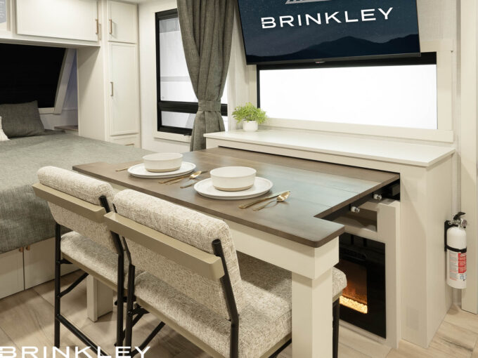 Pull-out dining table in the Brinkley Model I travel trailers, demonstrating smart design and versatile living space. The solid hardwood table expands when needed to a table or desk and features a built-in utensil drawer with heavy-duty glides, maximizing functionality in a luxury travel trailer. When not needed it takes up almost not space maximizing living space.