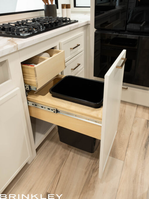 Integrated waste management solution in the Brinkley Model Ix 23x luxury travel trailer kitchen showing backup bag storage