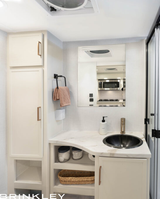 Luxury bathroom interior in a Brinkley Model Ix 23x travel trailer featuring residential fixtures and a porcelain foot-flush toilet
