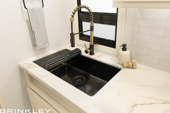 Brinkley RV Model Ix 23x residential kitchen featuring a stainless steel farmhouse sink with Tuff Coat protection and integrated dishwasher prep.